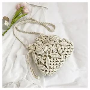 Detail of hand-woven beige bucket bag with hollow geometric patterns and drawstring