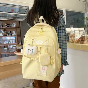 Détail d'un sac à dos en nylon jaune clair avec charme chat en peluche et mini pochette
