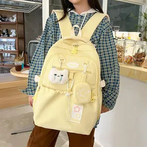 Détail du sac à dos en nylon jaune avec peluche chat et charms étoiles sur modèle
