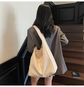 Detail of beige woven hobo shoulder bag with wide strap and spacious bucket design