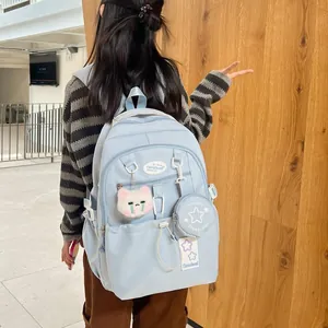 Sac à dos d'école bleu clair avec charm chat en peluche et pochette sur fond bois
