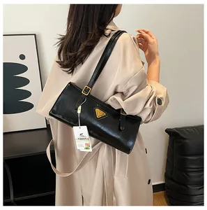 Nahaufnahme der schwarzen Lackledertasche mit goldenem Dreieckslogo und Schultergurt