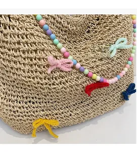 Close-up of woven straw tote bag with colorful beads and knitted bow decorations
