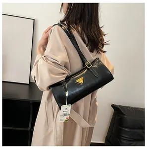 Detailansicht einer schwarzen Handtasche aus Lackleder mit goldenem Dreieckslogo am Riemen