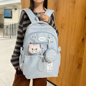 Détail d'un sac à dos étudiant bleu clair avec pochette étoile et accessoire chat sur mannequin
