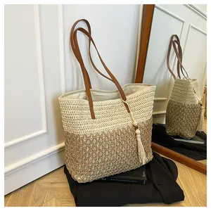 Detail of hand-woven straw tote with leather shoulder straps and tassel accessory