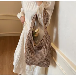 Detail of hand-woven straw tote bag with wide shoulder strap shown with white dress