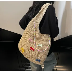 Detail of handmade woven tote bag with colorful bows and beaded strap on shoulder