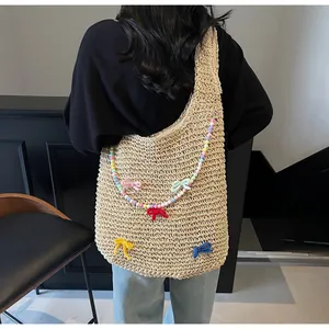 Detail of beige woven tote bag with colorful crochet bows and beaded strap on shoulder