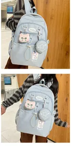 Détail du sac à dos scolaire bleu clair avec pendentif chat et mini porte-monnaie étoile