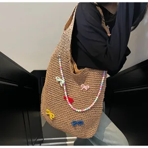 Detail of hand-woven straw tote with colorful beads and decorative fabric bow