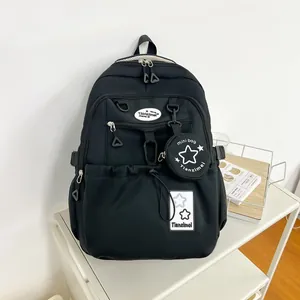 Détail du sac à dos scolaire noir avec motifs d'étoiles et un mini pendentif porte-monnaie