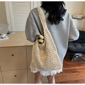 Detail of beige hollow woven bucket bag with wide shoulder strap for beach and casual use