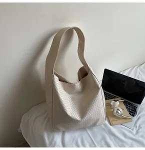Detail shot of cream woven tote bag showing premium texture and wide shoulder strap