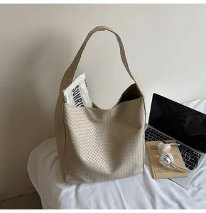 Detailed view of beige woven bucket bag with thick shoulder strap and large capacity