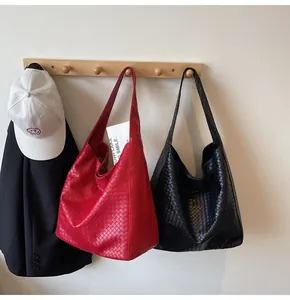 Detail of woven texture on red and black hobo bags hanging on hooks in a minimalist setting