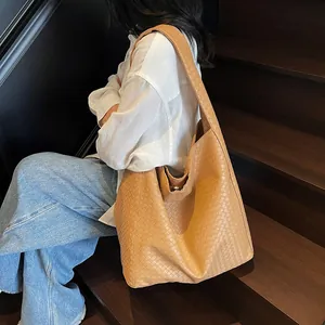 Caramel brown woven leather tote bag with wide strap in a minimalist hobo style
