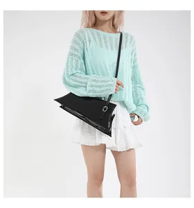 Détail d'un sac à épaule en cuir verni noir avec finition brillante et boucle argentée