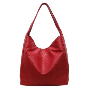 Large red woven leather bucket bag with wide shoulder strap in minimalist hobo style