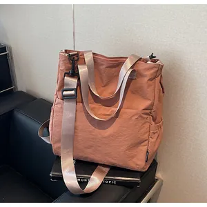 Detail van de koraalroze nylon draagtas met voorvak en verstelbare schouderbanden
