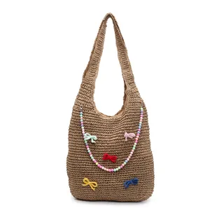Handwoven straw tote bag with colorful beads and small bows for summer beach vacation
