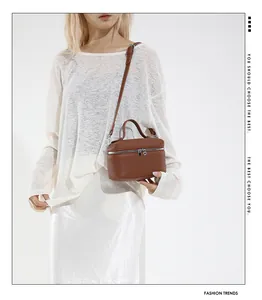 Sac bandoulière en cuir marron grainé porté avec une bandoulière réglable sur blanc