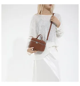Sac bandoulière marron en cuir grainé porté par un mannequin en tenue élégante