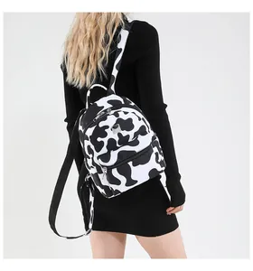 Detailed back view of a mini backpack with black and white cow print worn by a model