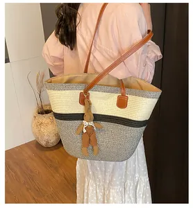Detail of woven tote bag featuring striped texture, leather straps and a cute rabbit charm