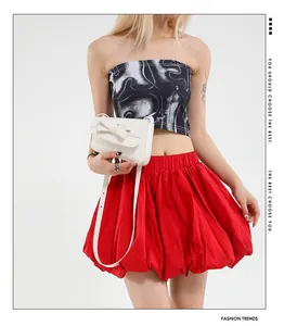 Close-up of minimalist white leather crossbody bag with a bow accent and red puff skirt