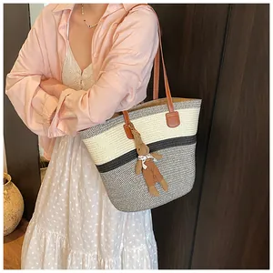 Detail of tricolor woven tote bag featuring leather handles and cute rabbit charm accessory