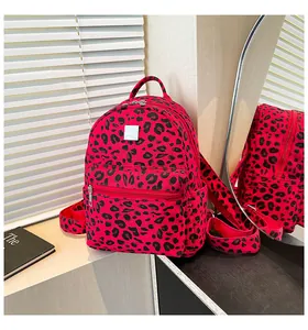 Close-up of red leopard print backpack showing front zipper pocket and side pockets