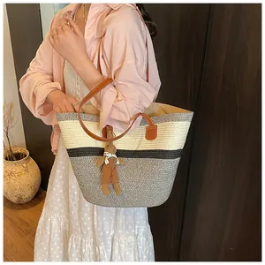 Close-up of tricolor straw woven tote bag with leather strap and cute bear charm pendant