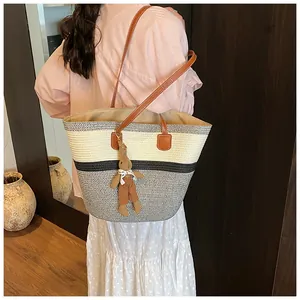 Detail of woven straw tote bag featuring contrast panels and cute rabbit charm accessory