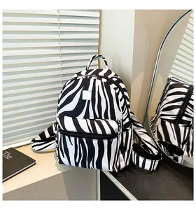 Close-up of zebra pattern backpack with dual zippers and handle in mirror reflection
