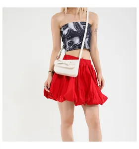 Close-up of white crossbody bag featuring a stylish bow on a red dress background
