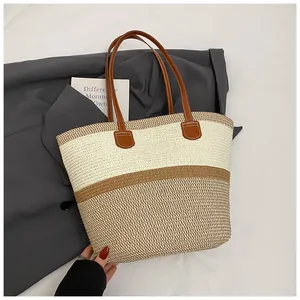Detail of two-tone woven tote bag featuring brown leather handles and summer straw texture