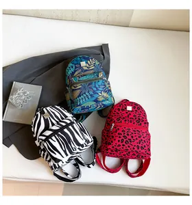 Detailed view of leopard, zebra, and jungle print mini backpacks with metal logos