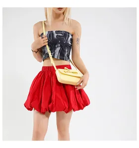Detail of light yellow bow crossbody bag worn by a model on a white background
