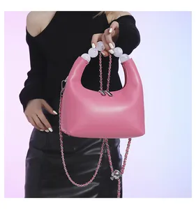 Vue détaillée du sac à main en cuir rose avec poignée en perles et bandoulière chaîne