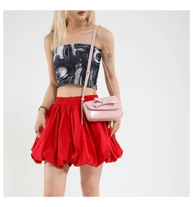 Detail of pink faux leather square bag featuring a delicate bow and adjustable strap