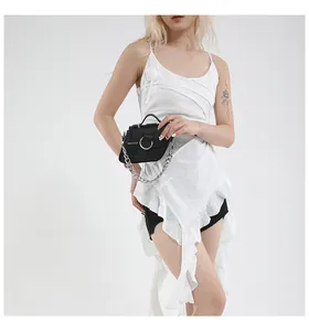 Détail de cuir grainé noir avec chaîne argentée et boucle métallique sur le sac à main