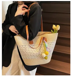Detail of hand-woven striped tote bag with floral patterns and colorful pompom charms