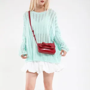 Chic light mint green open-knit sweater paired with a stylish red bow crossbody bag
