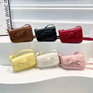 Minimalist small PU leather crossbody bags with bows in six colors shown on white steps