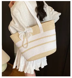 Dettaglio borsa tote in paglia a righe con grande fiocco bianco e ciondolo di perle