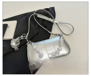Dettaglio borsa a mano argento metallizzato con cuciture quadrate e manico di perle