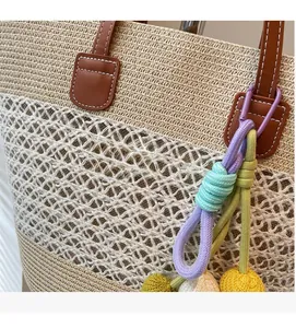 Detail of hand-woven straw tote with leather handles and colorful bohemian knot charms