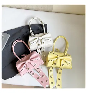 Détails de trois sacs à nœuds en cuir verni blanc, rose et jaune avec des rivets métalliques