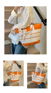 Dettaglio della borsa tote a righe in paglia con fiocco di raso bianco e ciondolo di perle